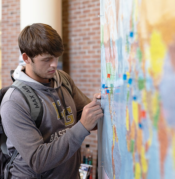male student placing pin on map
