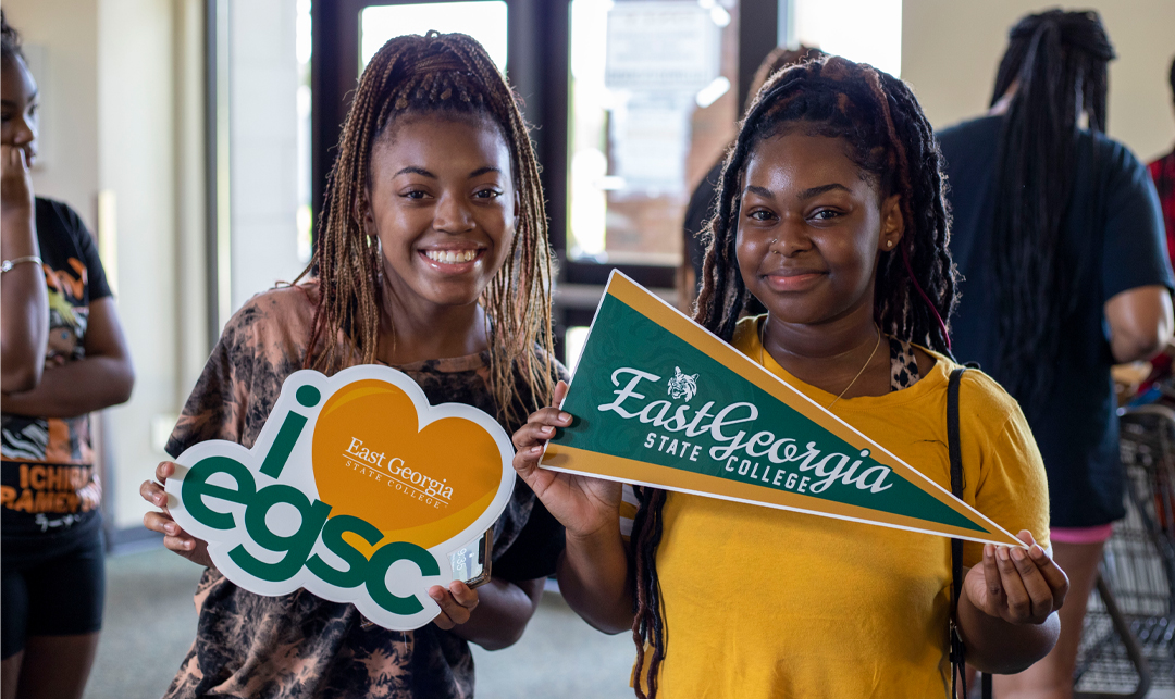 three students posing with EGSC signs